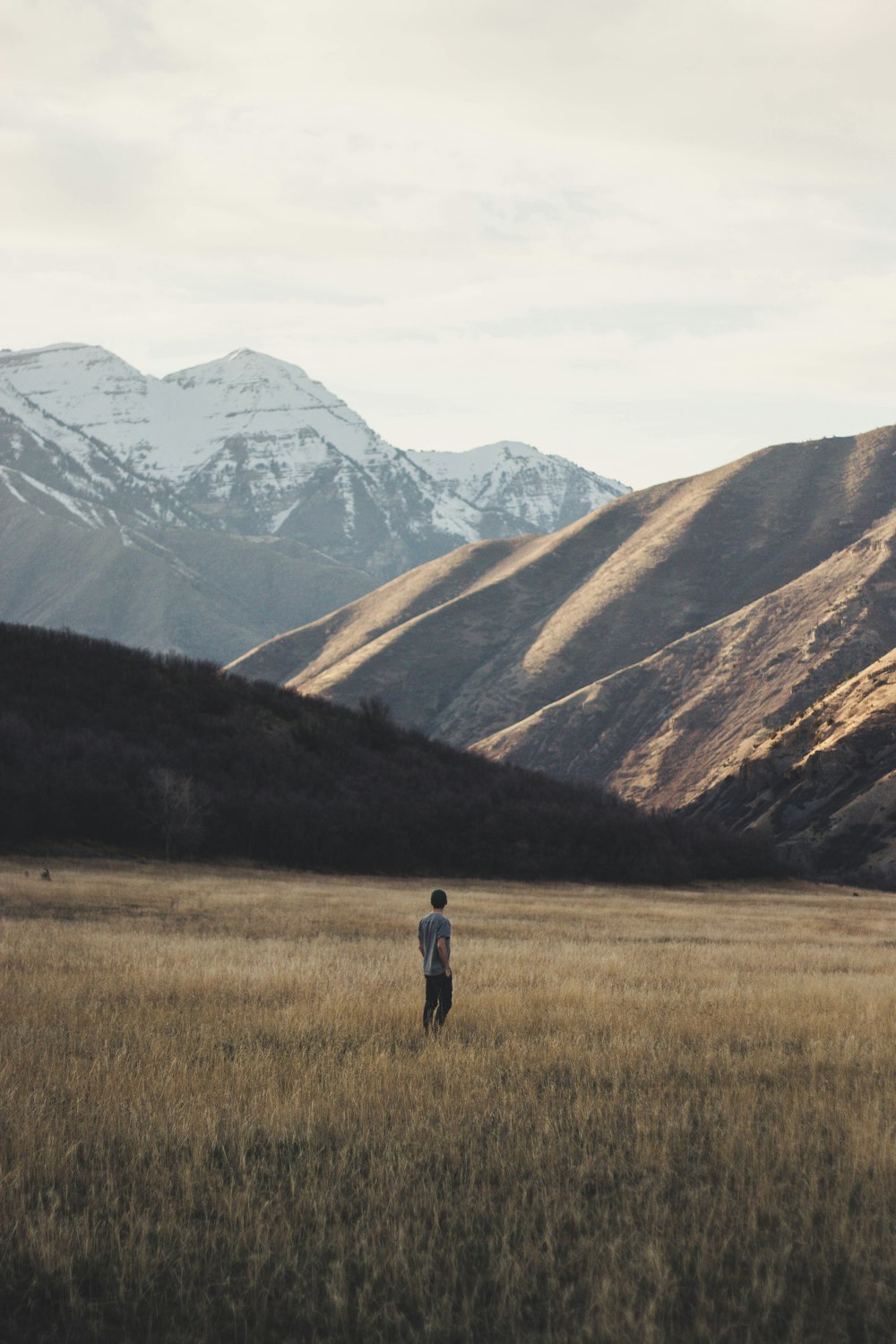 homem em pé no campo aberto perto da montanha durante o dia