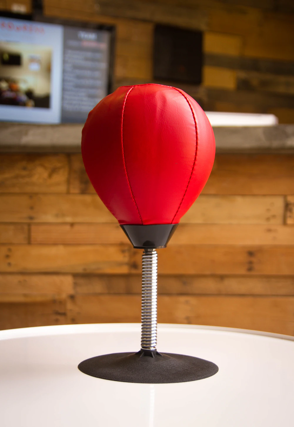 A red and black speed bag hanging in the gym