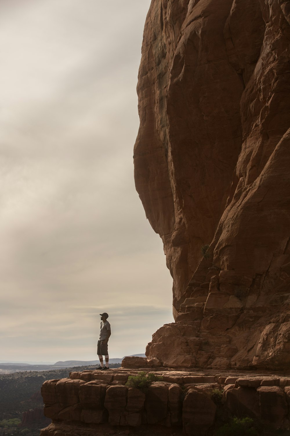 man standing at cliff of brown mountain
