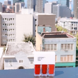 Urban cityscape background with a person applying serum, illustrating skincare designed for active city living.