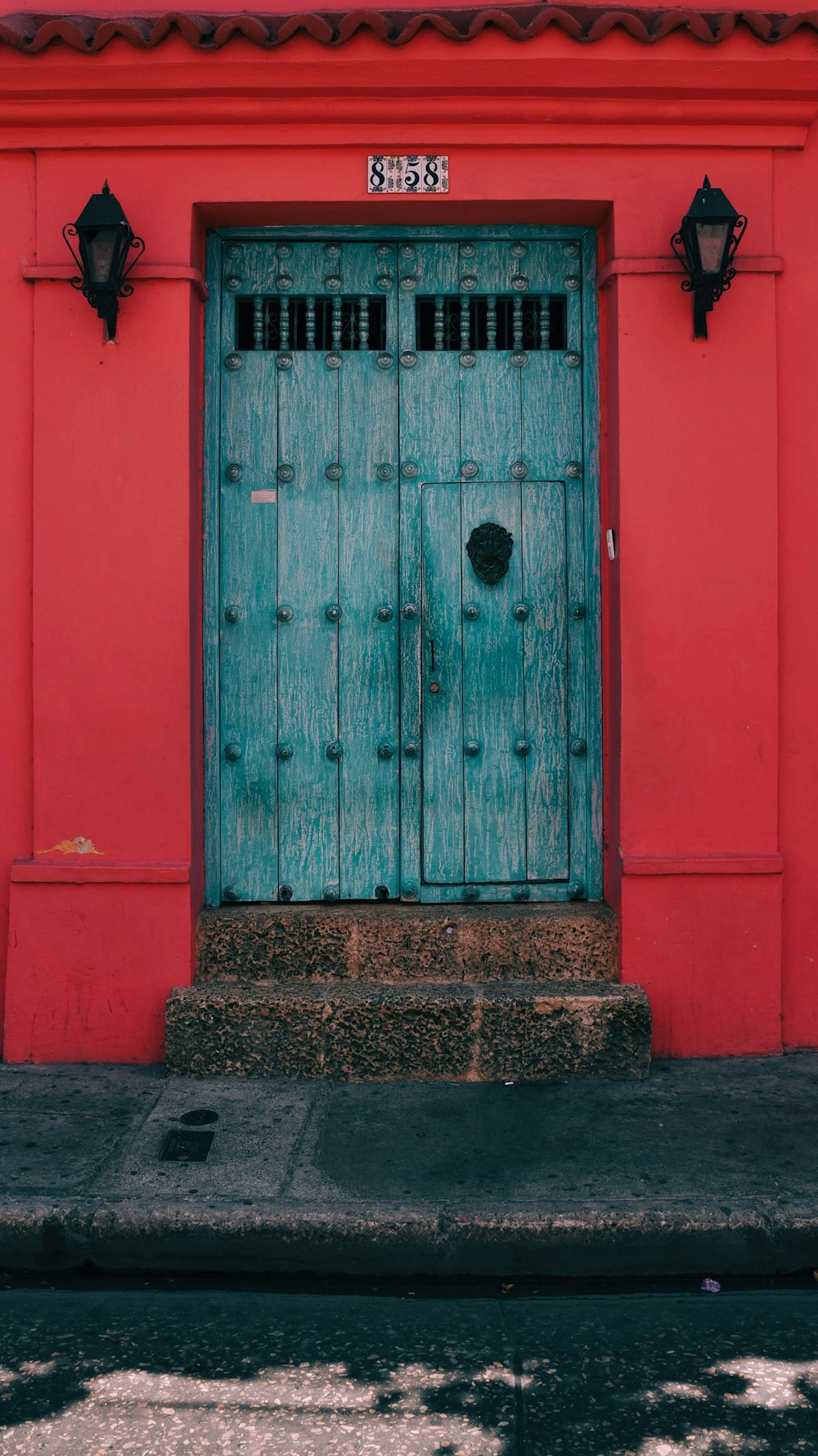 blue wooden door in red wall with light sconces
