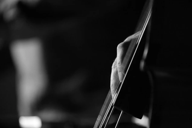 Black and white close-up of muao playing an instrument in a minimalist studio setting.