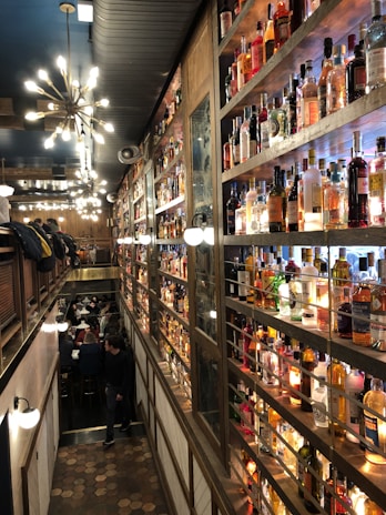 Cozy bar interior with warm lighting and bottles lined up on wooden shelves.