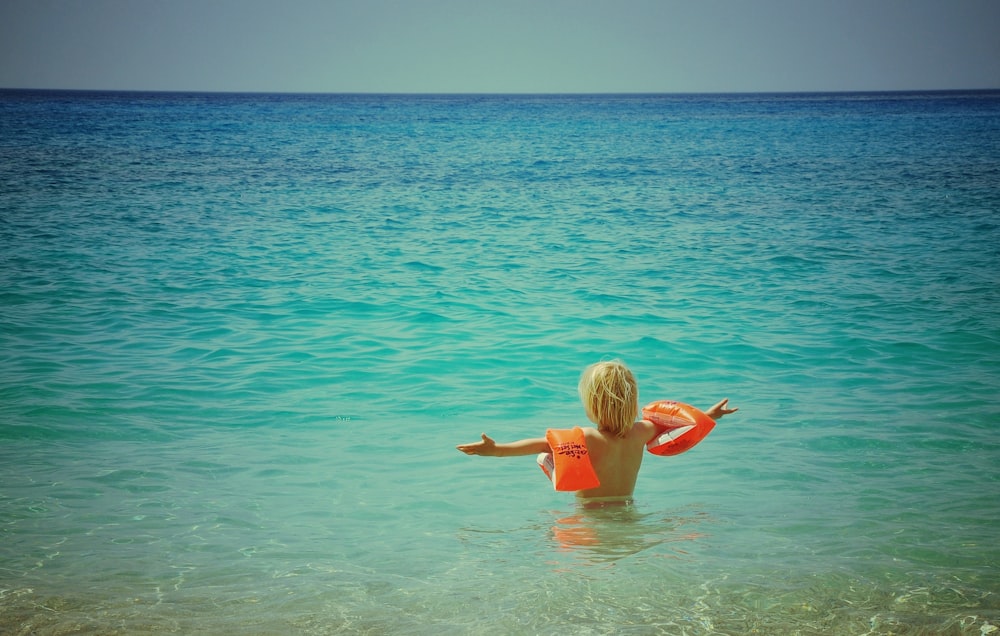 boy swimming on blue water