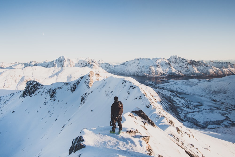 person standing on mountain overlooking sky