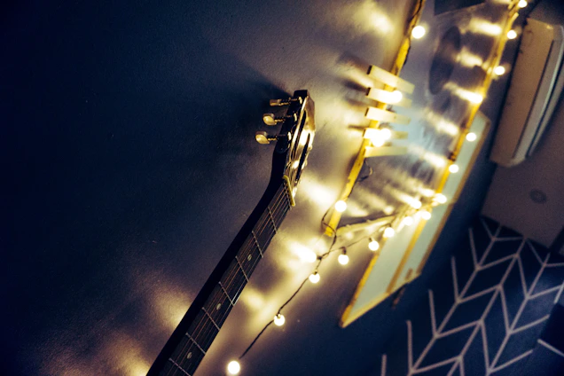 Yasheita smiling warmly while holding her guitar, surrounded by her favorite photography shots pinned on a cozy wall.