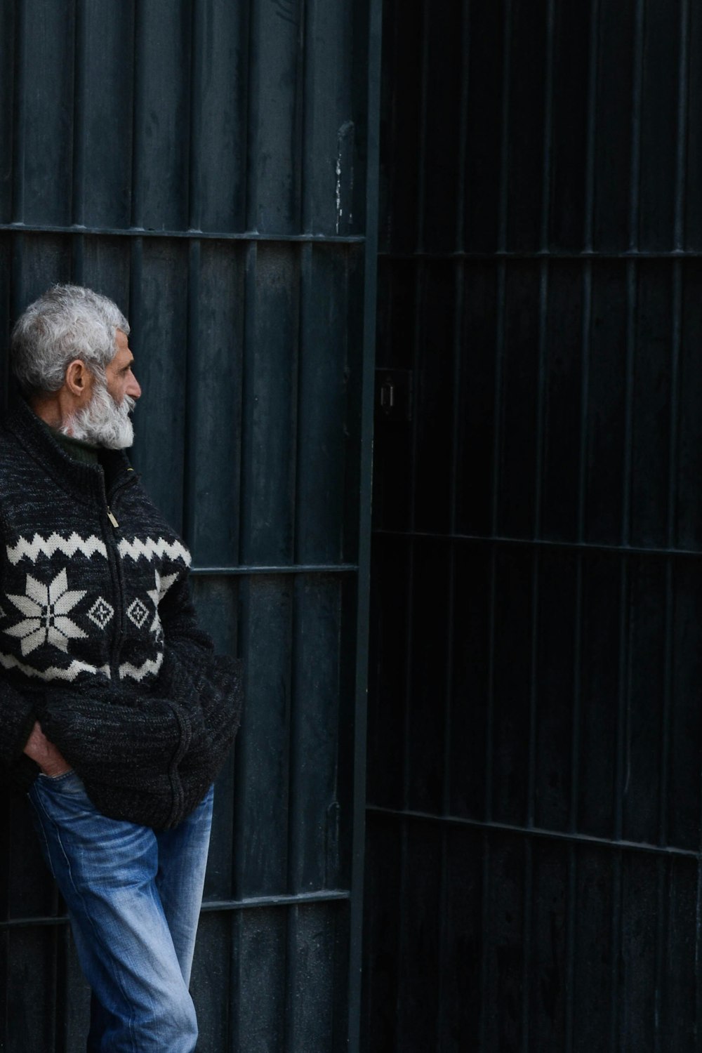 man standing while leaning on black gate