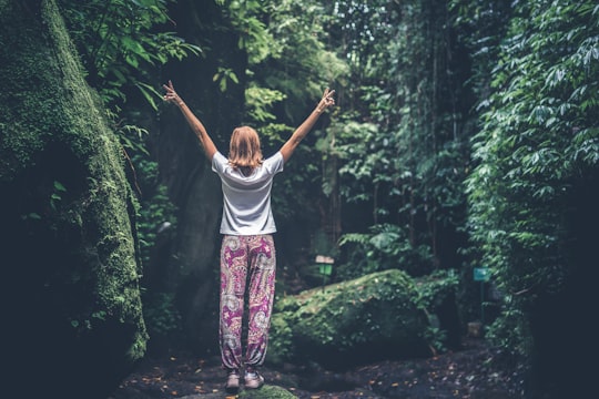 woman standing on rock making peace sign in forest in Bali Indonesia