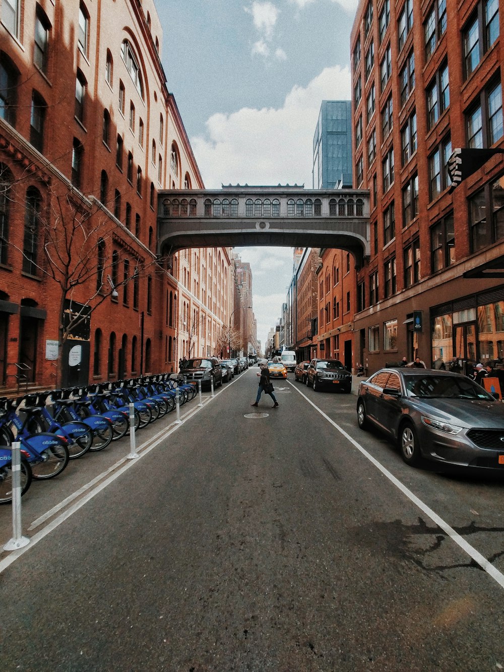 person crossing asphalt road between buildings