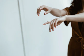 Close-up of senior hands gracefully moving through tai chi poses with a deep teal background.