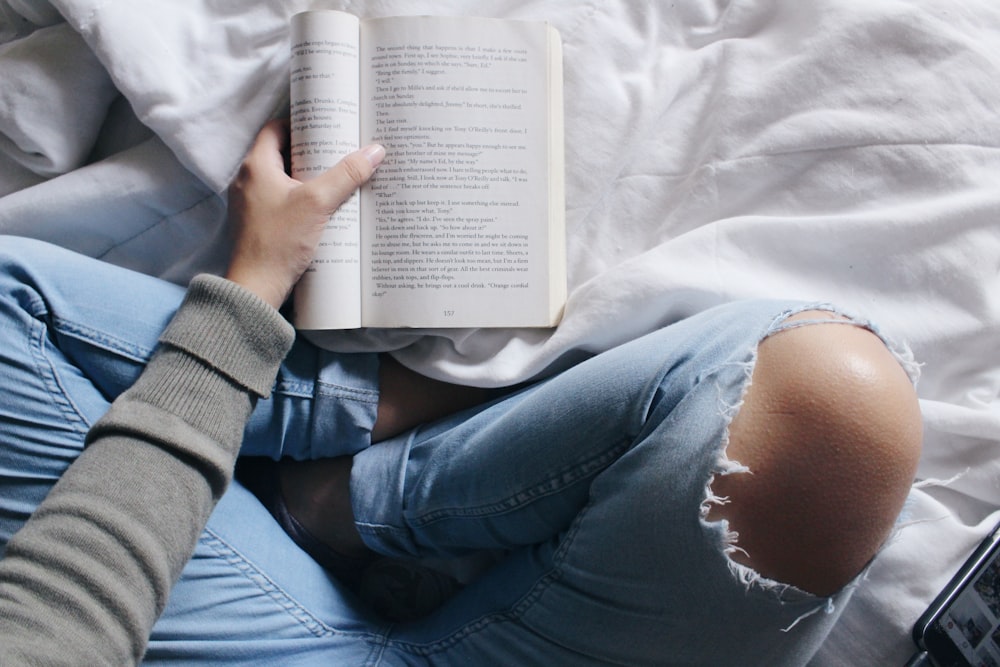 person reading book sitting with cross legs