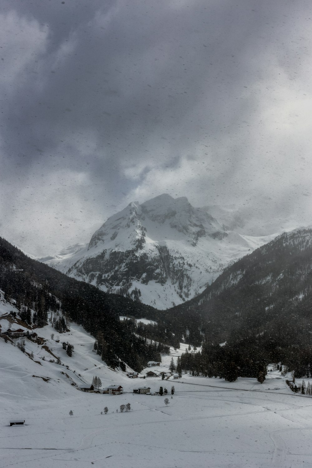 Graustufen des Alpengebirges, das von dunklen Wolken bedeckt ist