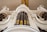 An ornate pipe organ with intricate detailing is depicted. The image captures the impressive vertical structure of the organ pipes, surrounded by decorative carvings and embellishments. Two figures, possibly angels, emerge from the sides, each holding a trumpet.