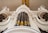 An ornate pipe organ with intricate detailing is depicted. The image captures the impressive vertical structure of the organ pipes, surrounded by decorative carvings and embellishments. Two figures, possibly angels, emerge from the sides, each holding a trumpet.