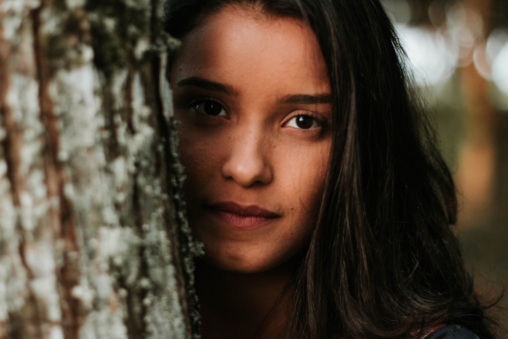 woman peeking on tree