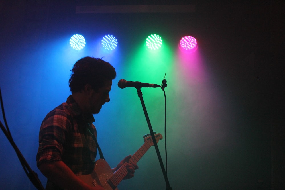 man playing guitar with stage lights