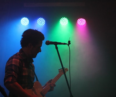 man playing guitar with stage lights