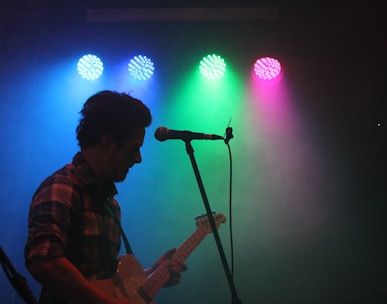 man playing guitar with stage lights