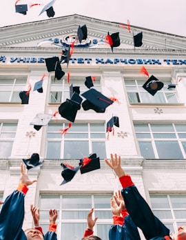 group of fresh graduates students throwing their academic hat in the air