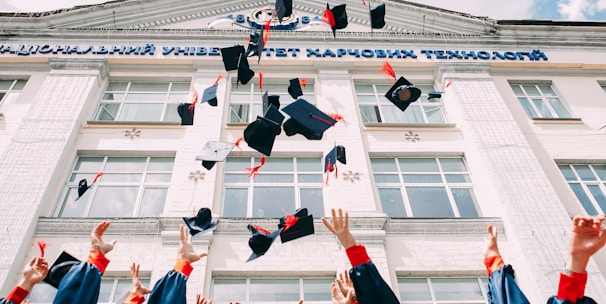 group of fresh graduates students throwing their academic hat in the air