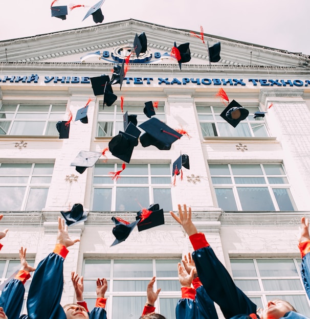 group of fresh graduates students throwing their academic hat in the air