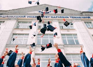 group of fresh graduates students throwing their academic hat in the air