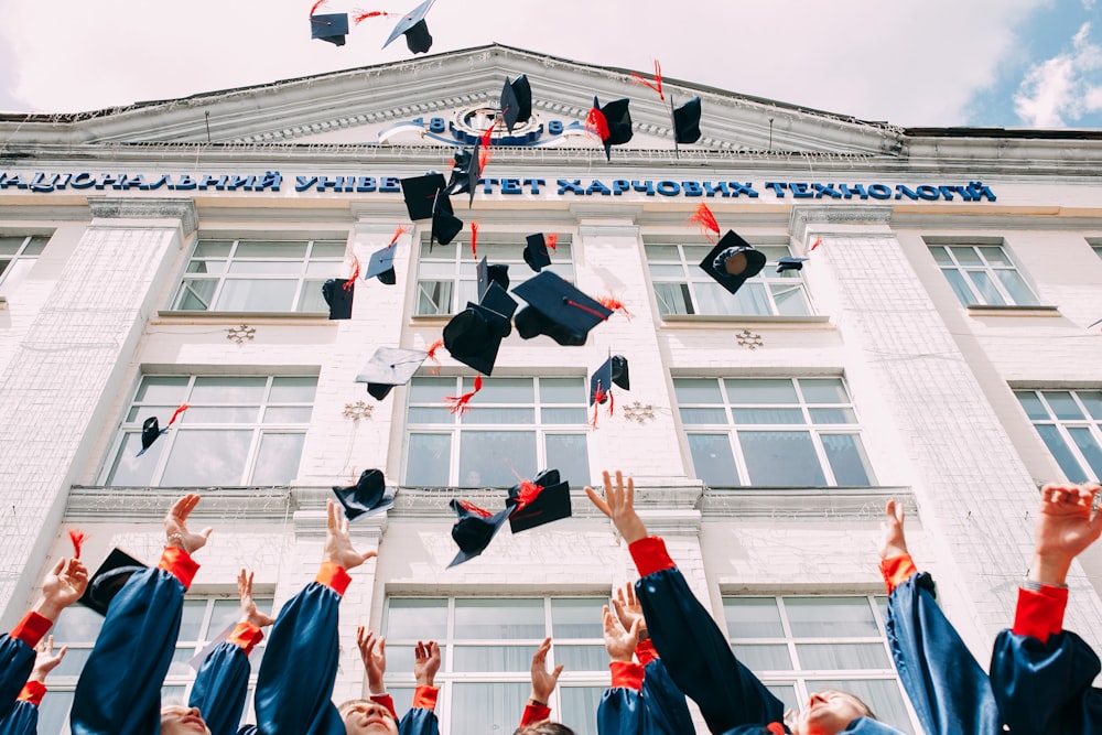 gruppo di studenti neolaureati che lanciano il loro cappello accademico in aria