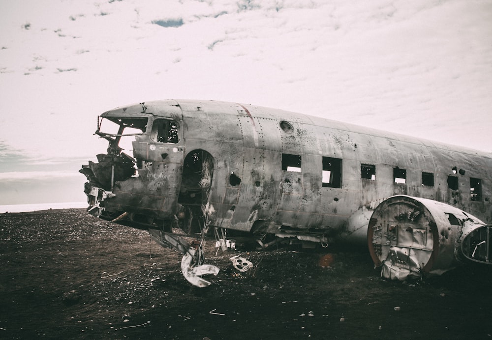 Foto em tons de cinza de avião abandonado em campo aberto