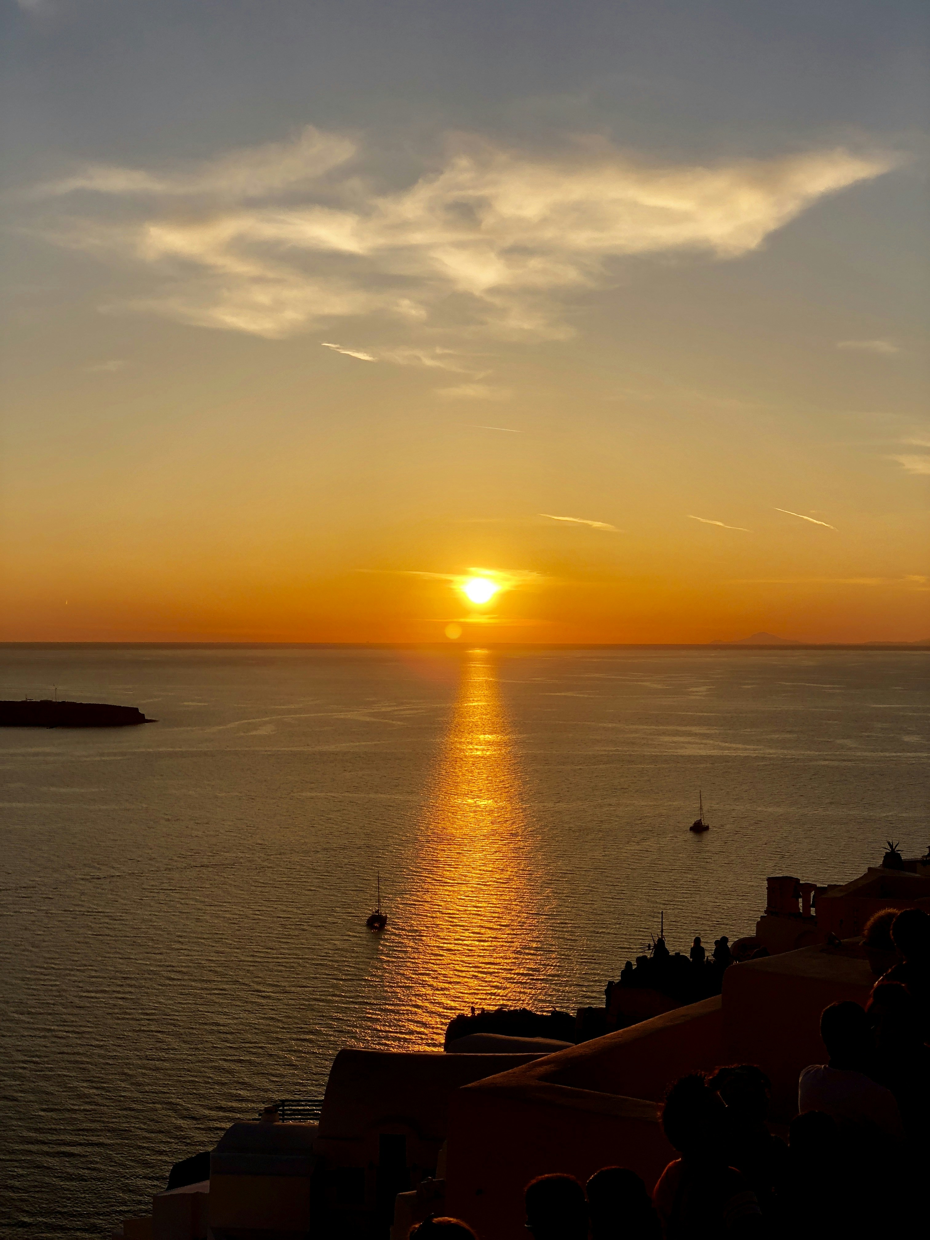 body of water, sailboats, and group of people during sunset