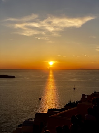 body of water, sailboats, and group of people during sunset