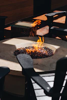 Close-up of a fire pit glowing warmly with comfortable chairs arranged around it.