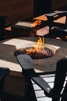 Evening shot of a fire pit casting soft light on rustic outdoor furniture.