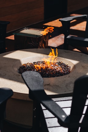 Comfortable outdoor seating arranged around a gentle fire pit at dusk.