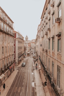 vehicles travelling on road between buildings during daytime