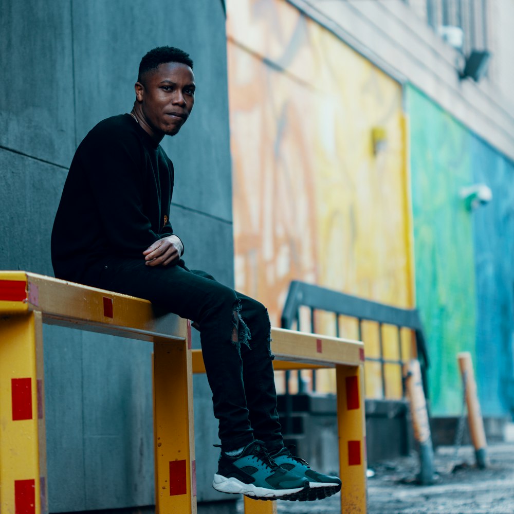 man sitting on yellow rails