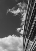 A striking black-and-white photo of a modern glass building reflecting the sky.