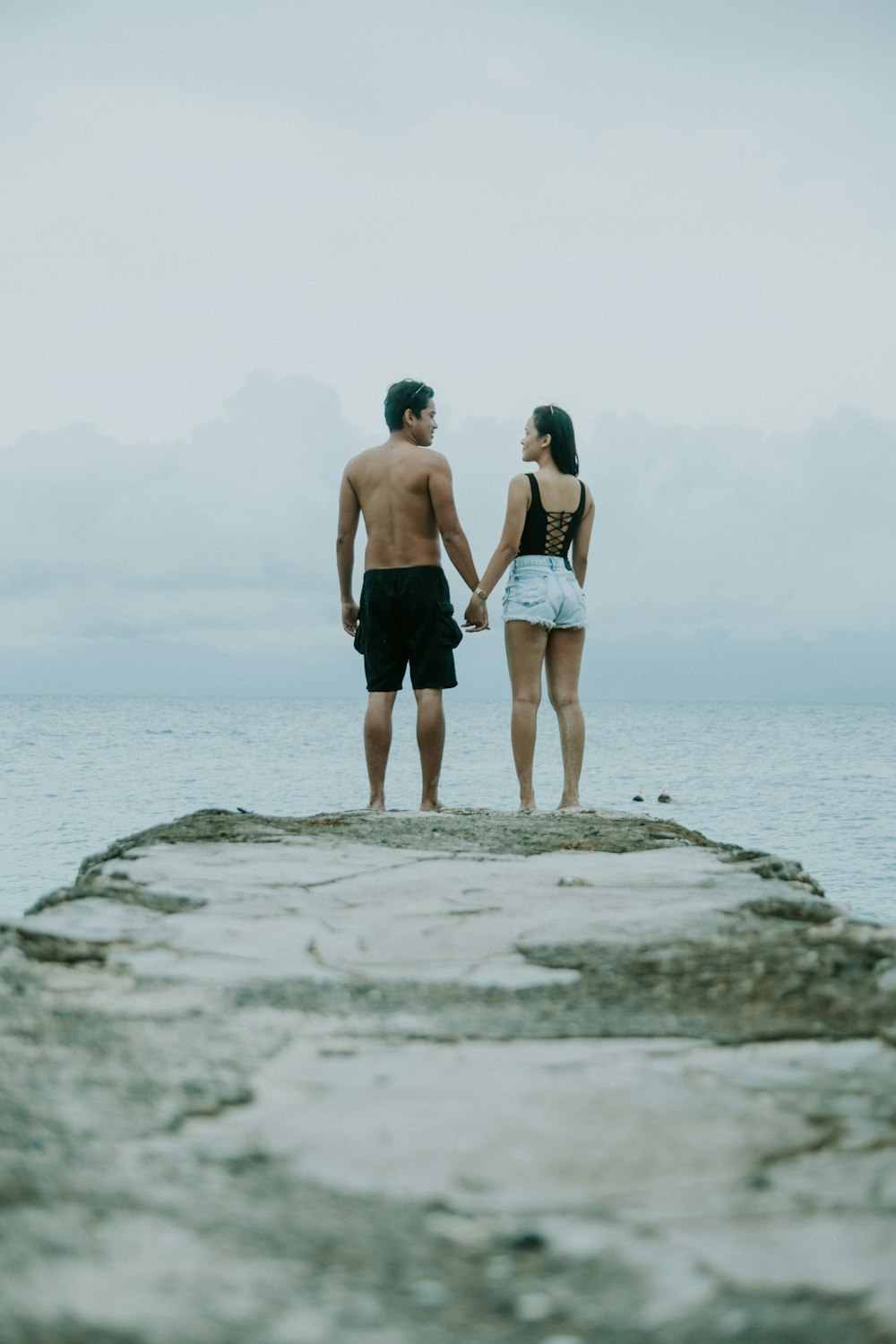 homme et femme se tenant la main debout sur le bord de la falaise