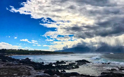A wide shot of a dramatic coastline under a cloudy sky, waves crashing on rocks