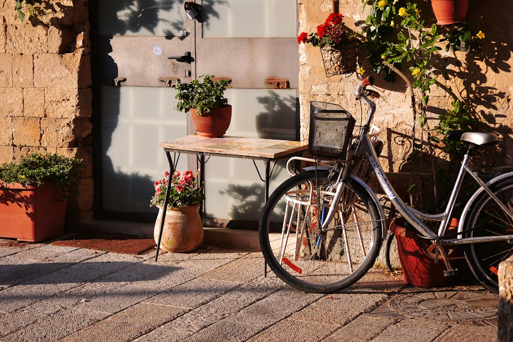 bicicleta cruiser cinza estacionada perto da mesa com planta no topo