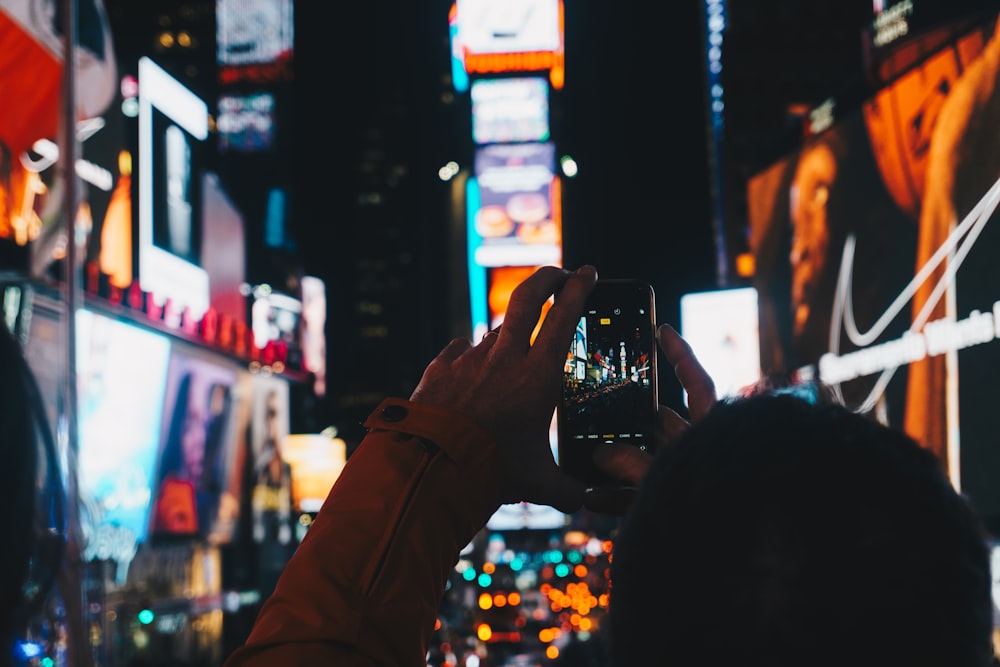 man taking photo of street using smartphone