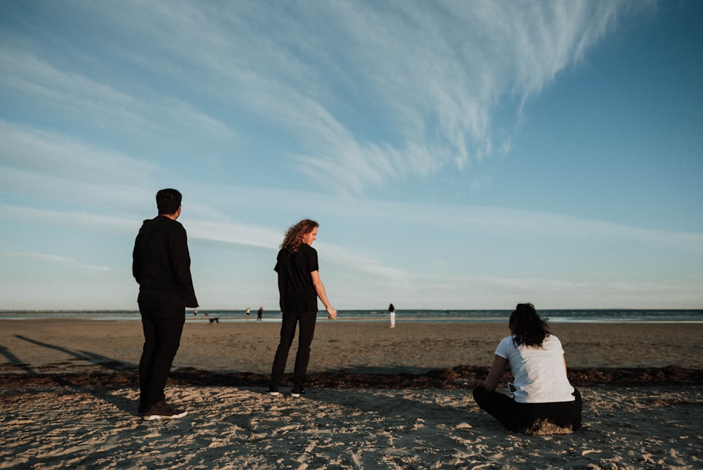 three person standing near seashore