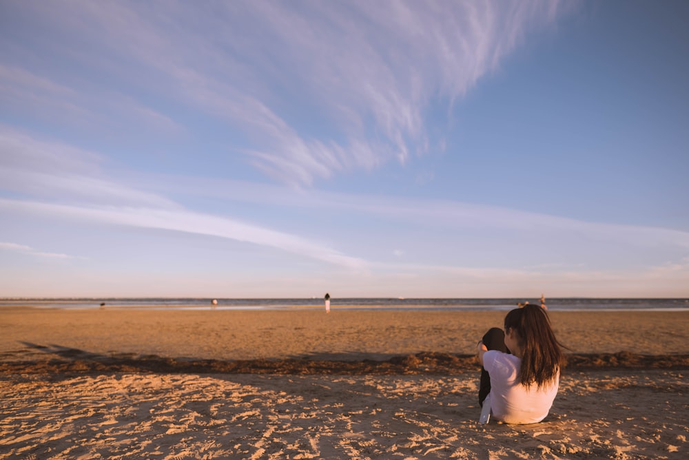 Mulher sentada na areia perto do oceano
