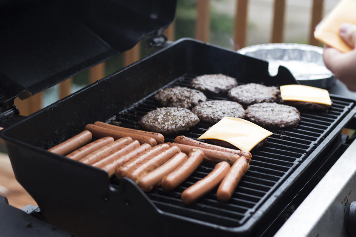 Juicy burgers and hot dogs cooking on an outdoor grill for a backyard barbecue party