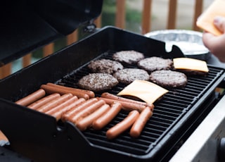 person standing in front grill grilling sausage