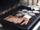 person standing in front grill grilling sausage