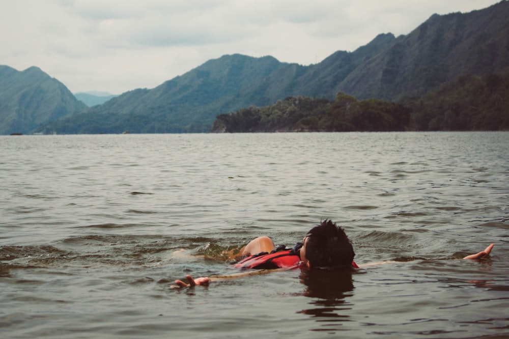 man floating on lake under dark sky