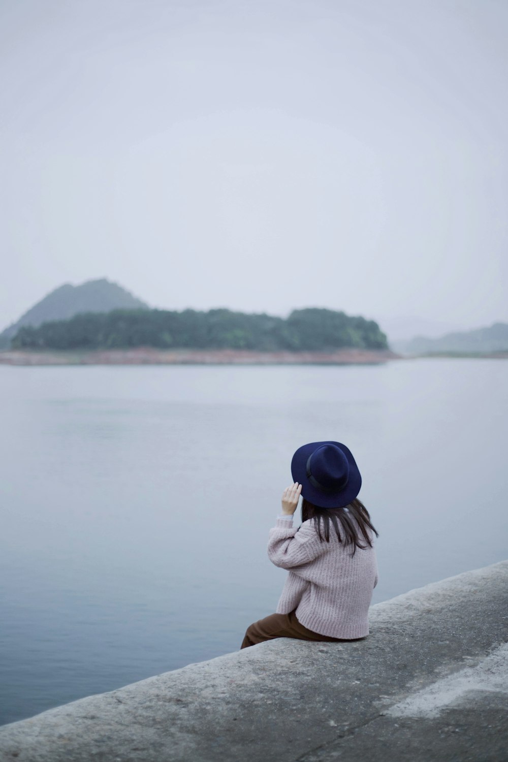 수역 앞 콘크리트 가장자리에 앉아 있는 여자