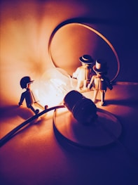 selective focus photography of three men figurines near lighted light bulb