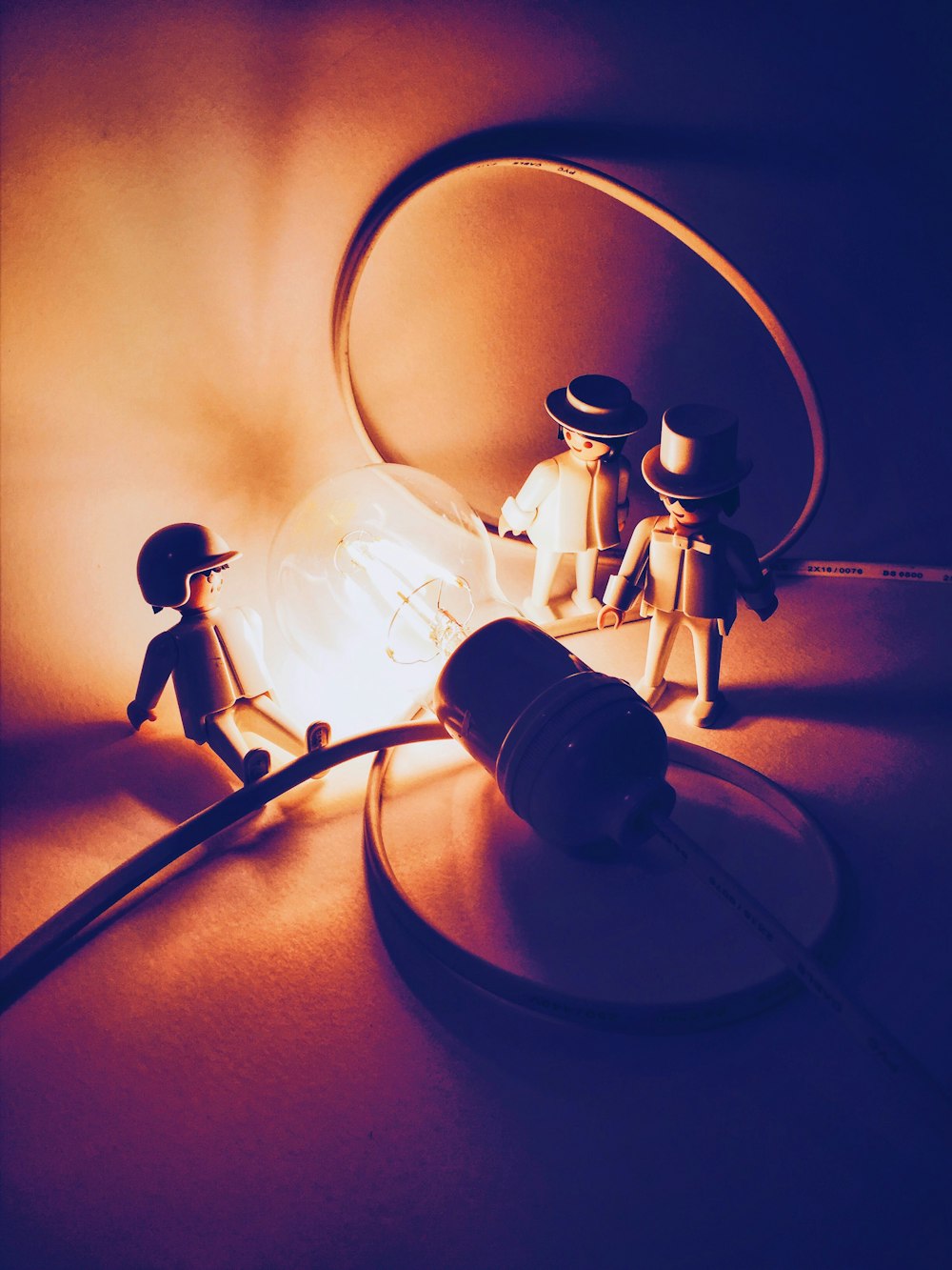 Photographie sélective de trois figurines d’hommes près d’une ampoule allumée