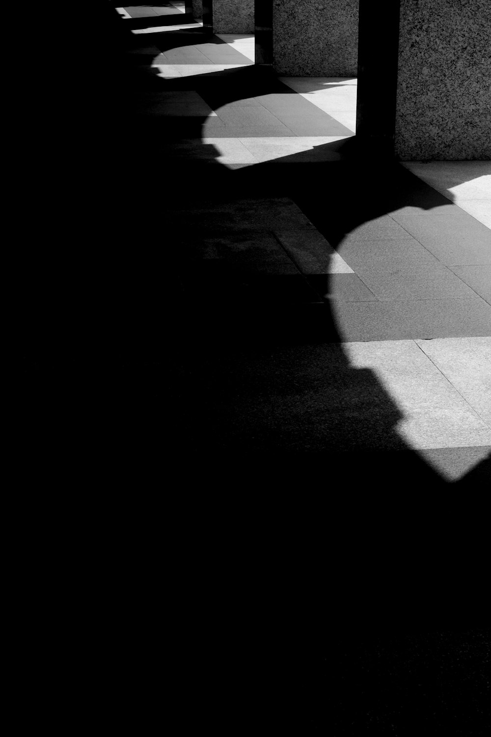a shadow of a person walking down a sidewalk